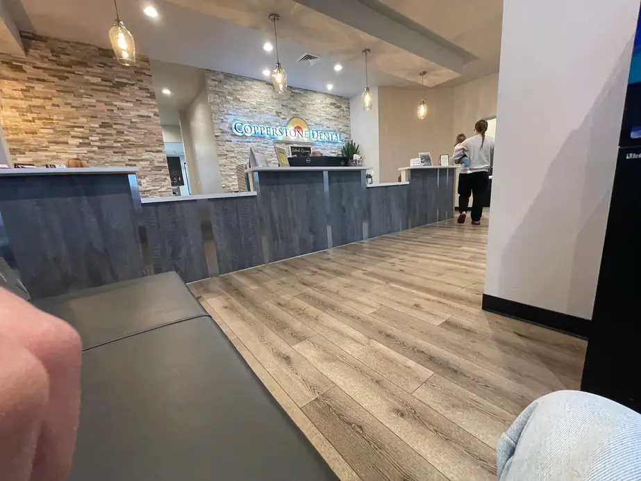 Reception at Copperstone Dental, with the practice name backlit on the stone accent wall